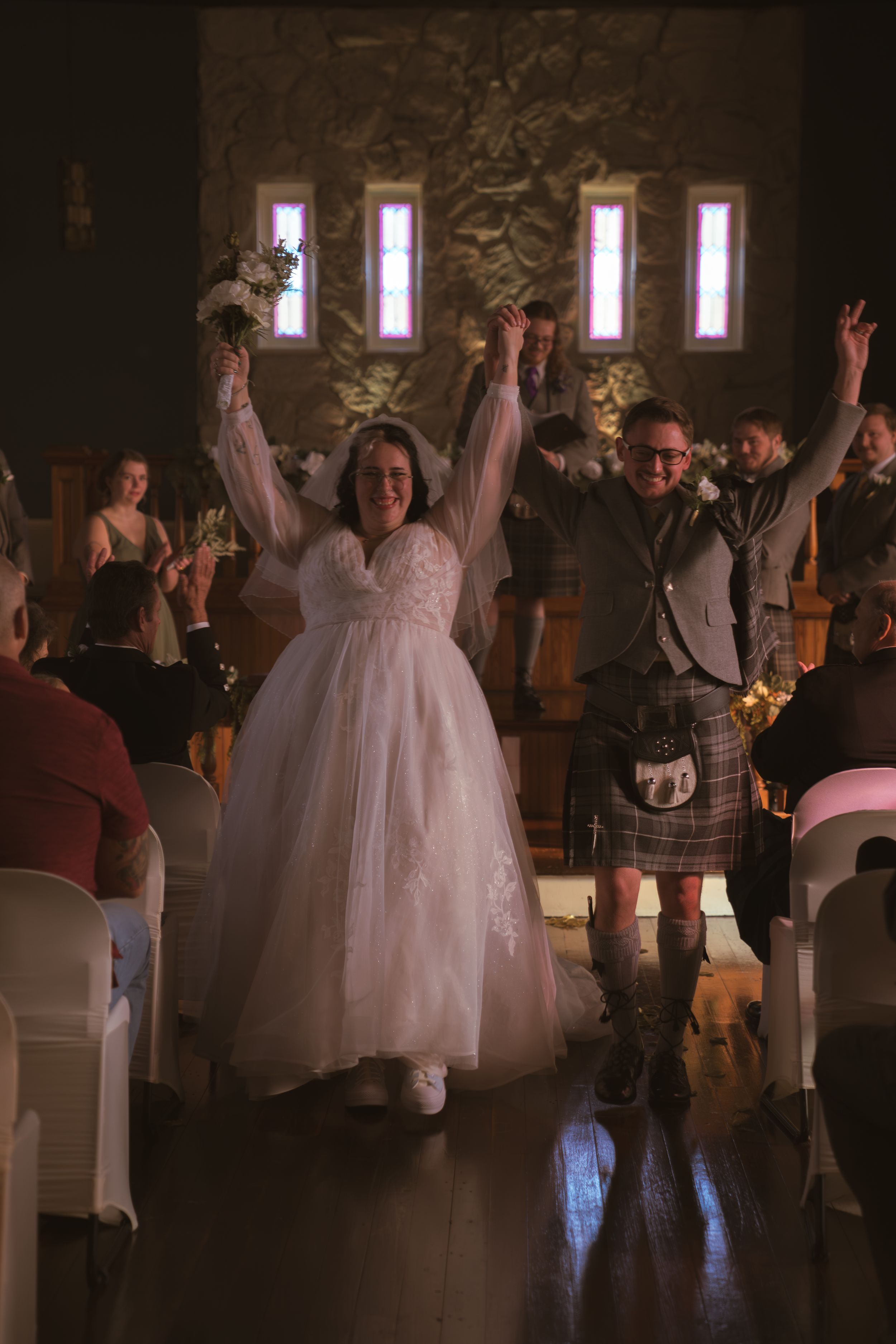 Wedding celebration in a rustic venue with guests dancing and celebrating.