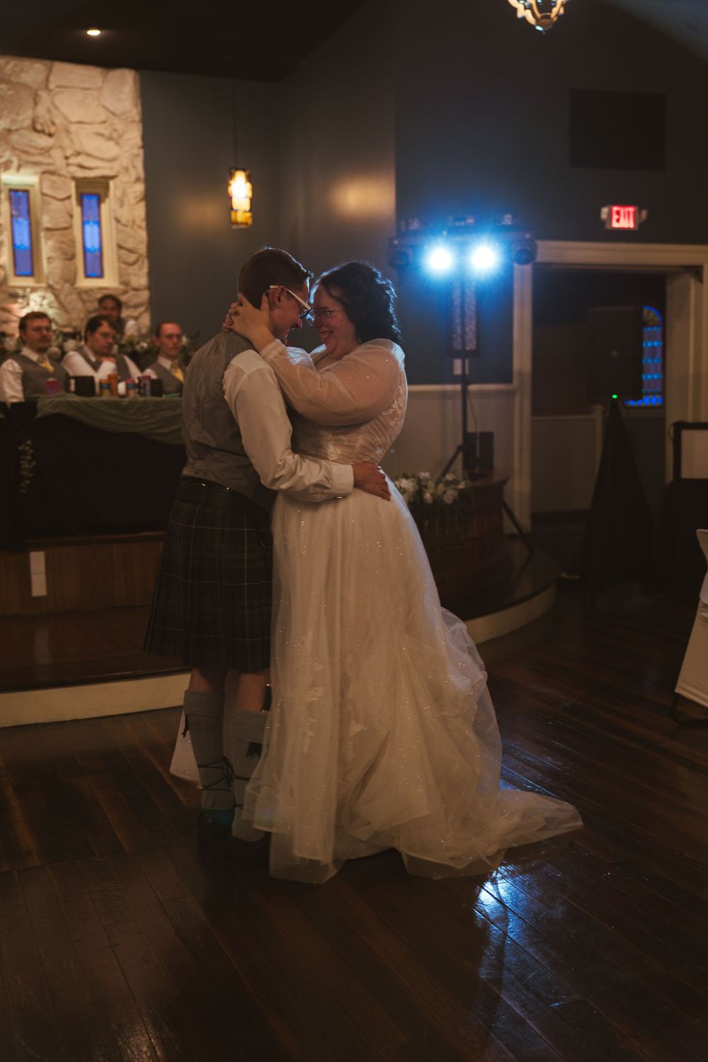 First dance at wedding reception in rustic venue with stone walls and mood lighting.