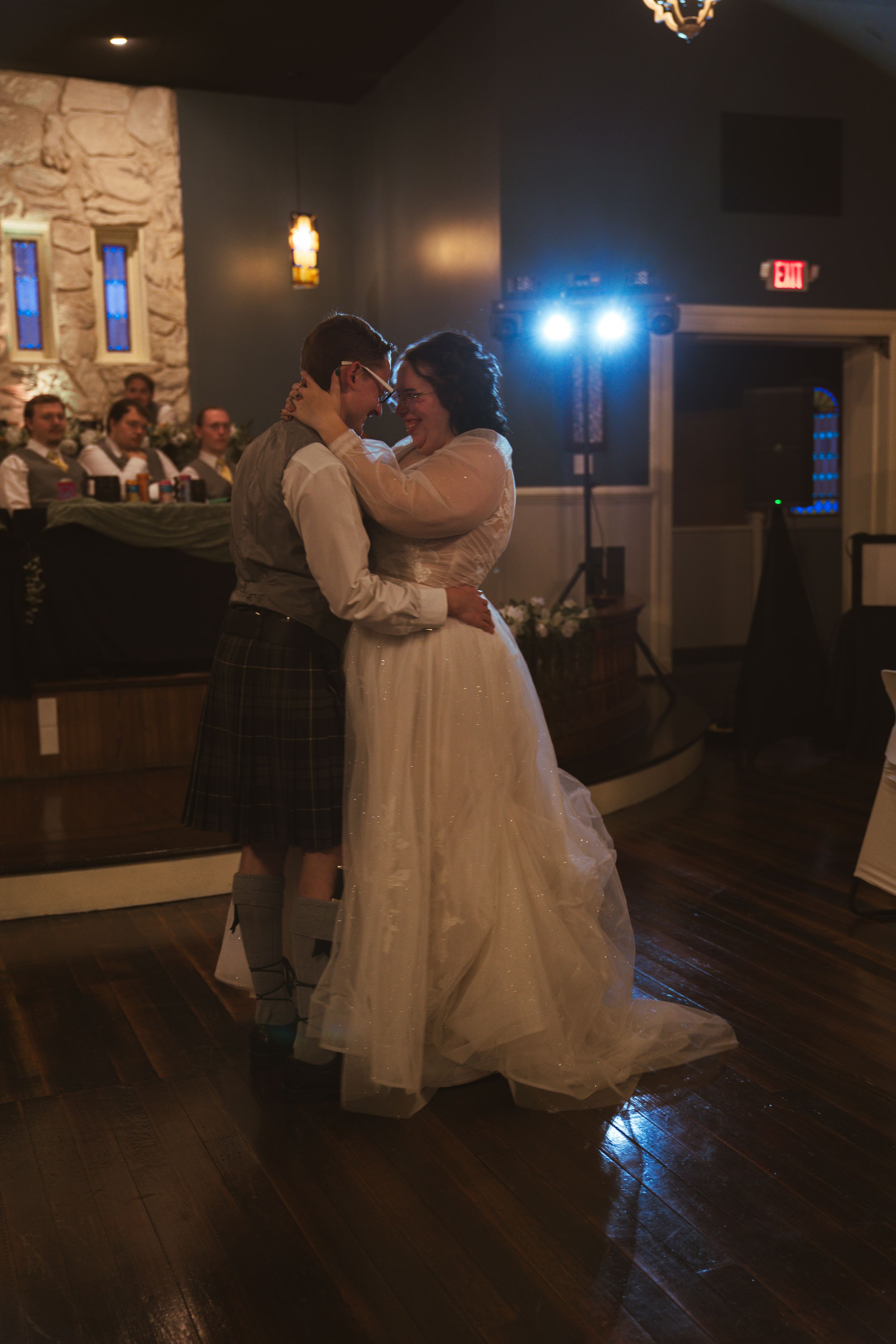 First dance at wedding reception in rustic venue with stone walls and mood lighting.