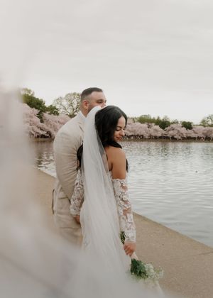Newlyweds share tender moments along the Tidal Basin during cherry blossom season.