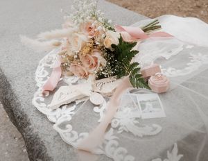 Delicate pink roses and wedding stationery styled with lace details.