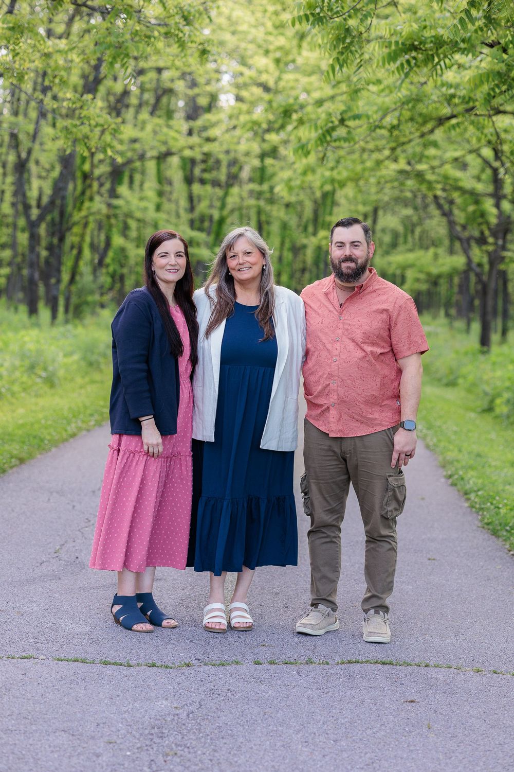 Family group standing together on a wooded path wearing coordinated spring outfits.