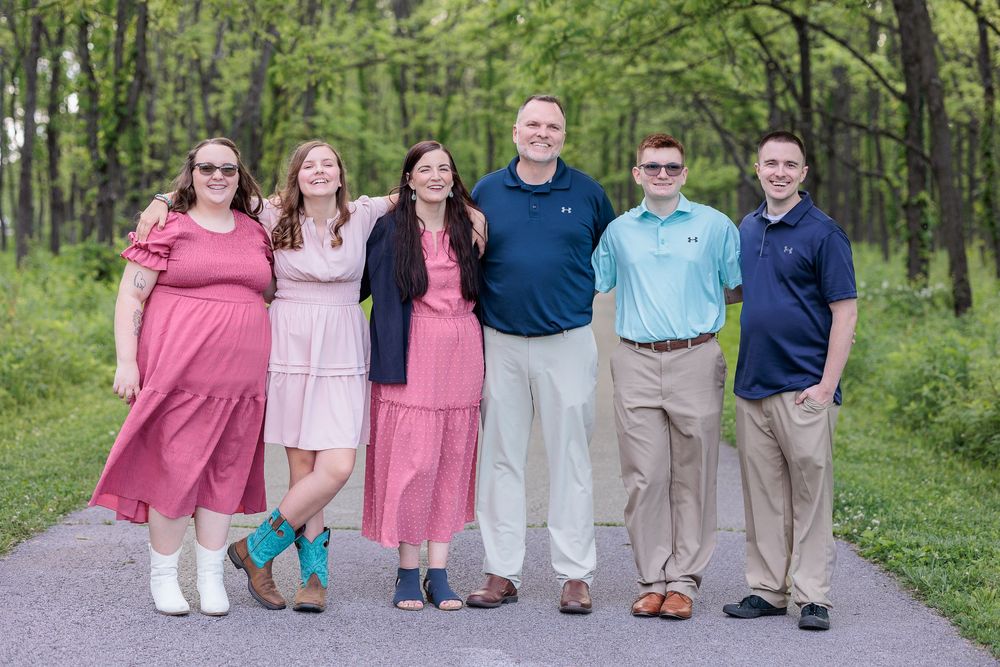 A family stands together on a wooded path wearing coordinated pink and blue outfits at Ft. Benjamin Harrison  State Park.