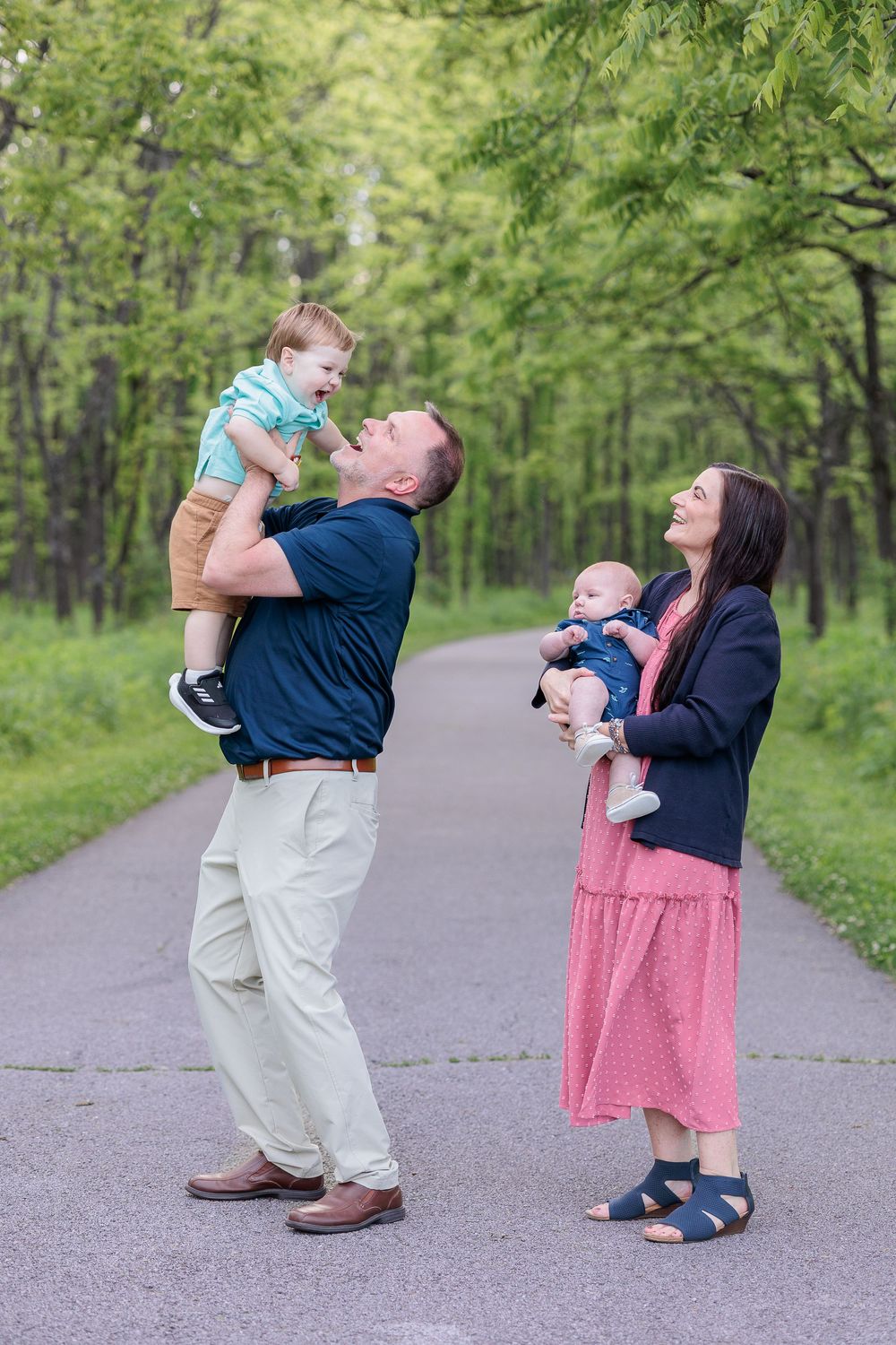 Playful interaction between people on a tree-lined path in springtime.