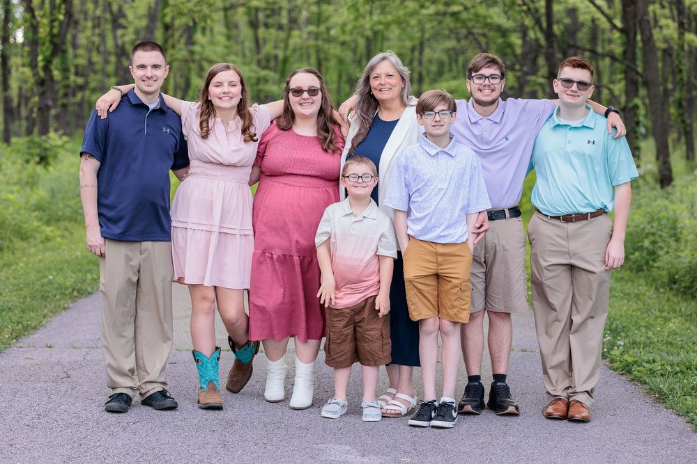 Family members lined up on a wooded path wearing coordinated casual outfits.