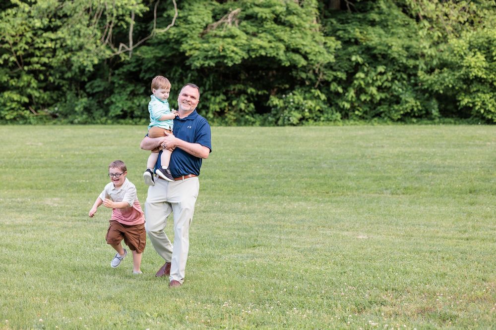 Grandparent and child playing together in a grassy field on a sunny day.