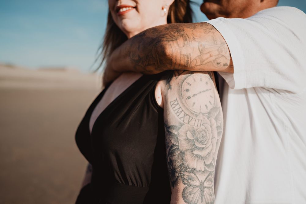 Detalle de tatuajes en una sesión romántica en la playa