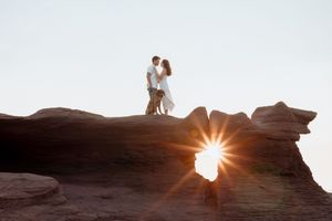 Adventure photography Shediac photographer  New Brunswick engagement photos couple standing on rocky cliff at sunset romantic photos Moncton
