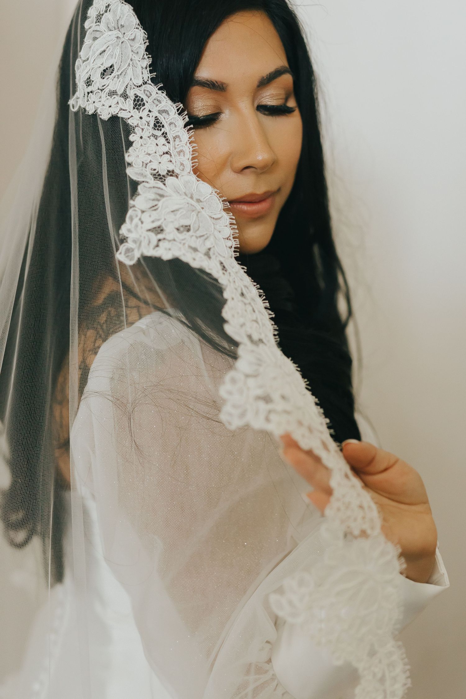 Close up detail of intricate lace wedding veil with soft romantic lighting.