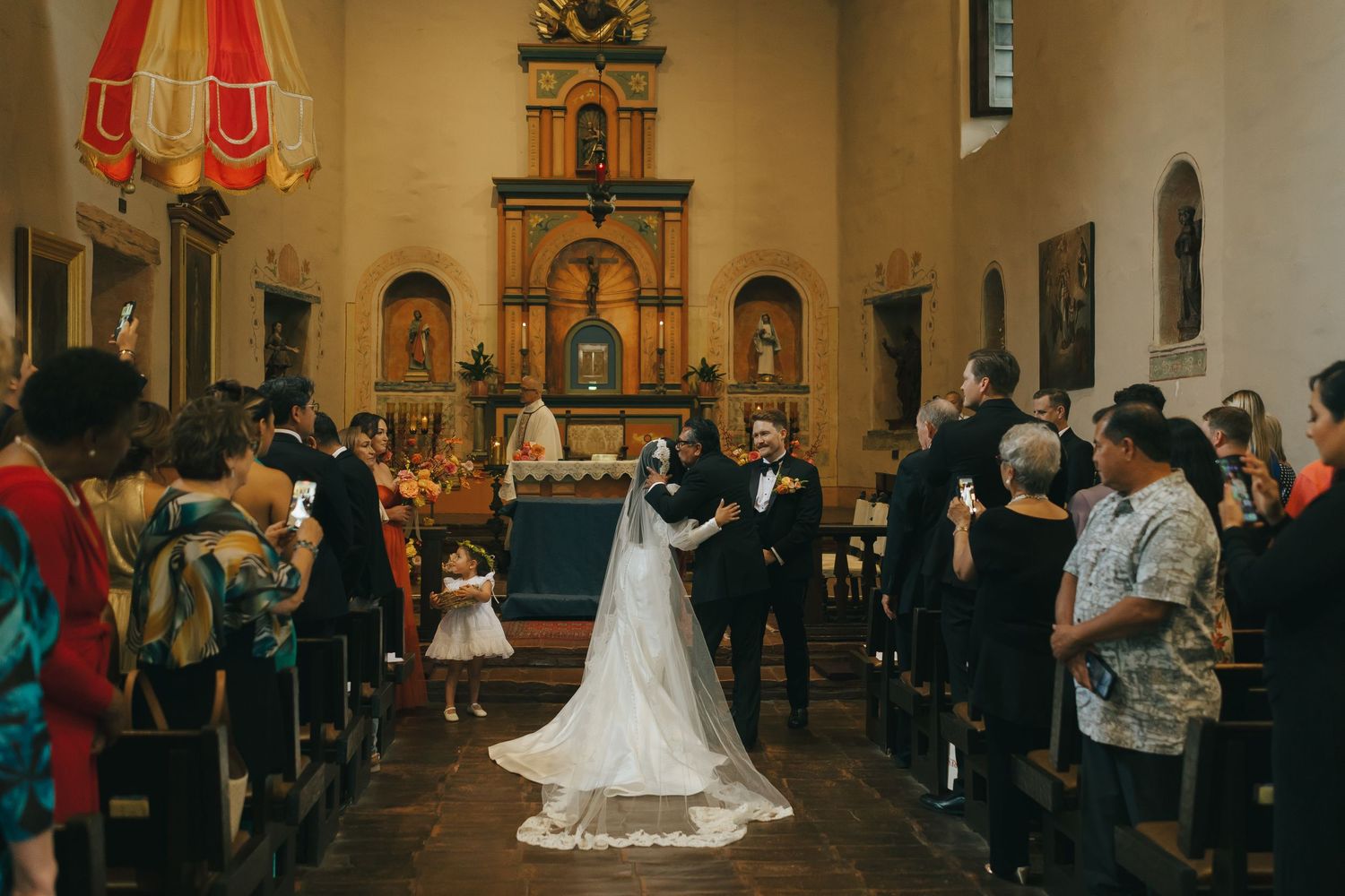 Wedding ceremony taking place in historic church interior with elegant decor and gathered guests in the pews.