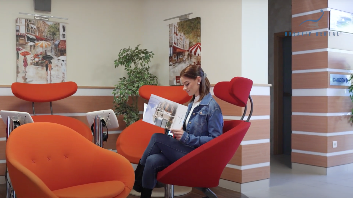 Patient relaxes in bright orange and red lounge chairs while reading in a modern lobby area
