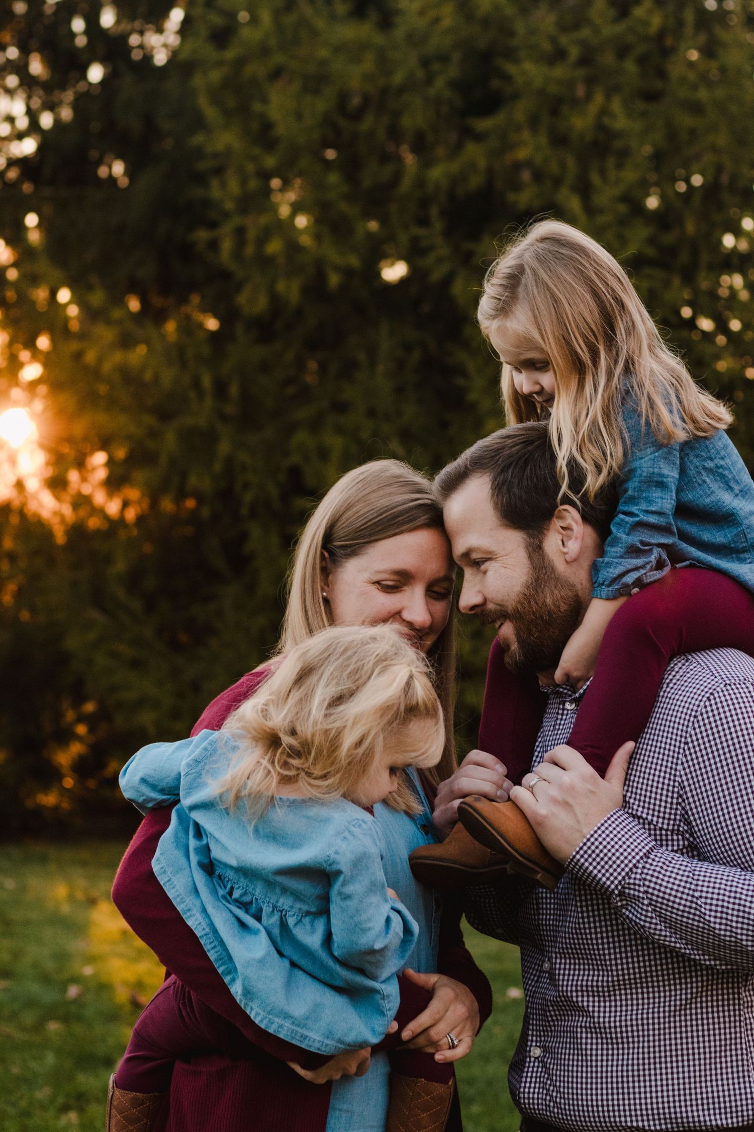 Family smiling with daughter on father's shoulders during lifestyle family photography session in South Lyon, Michigan.