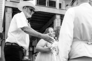 A candid black and white photograph capturing an interaction between people outdoors in a casual setting.