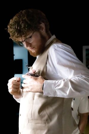 A person wearing a white shirt and beige apron ties the apron strings behind their back in a sequence of actions.
