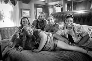 A candid black and white photograph of friends laughing together while lounging on a couch.