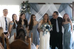 Wedding ceremony guests seated in rows with blue and white decor and floral arrangements.