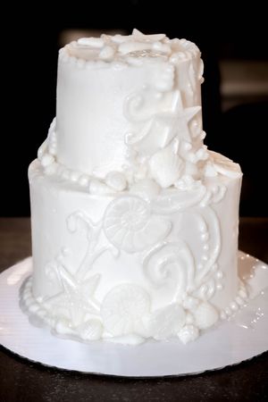 A series of close-up shots showing a white wedding cake with textured frosting and pearl-like decorative details.