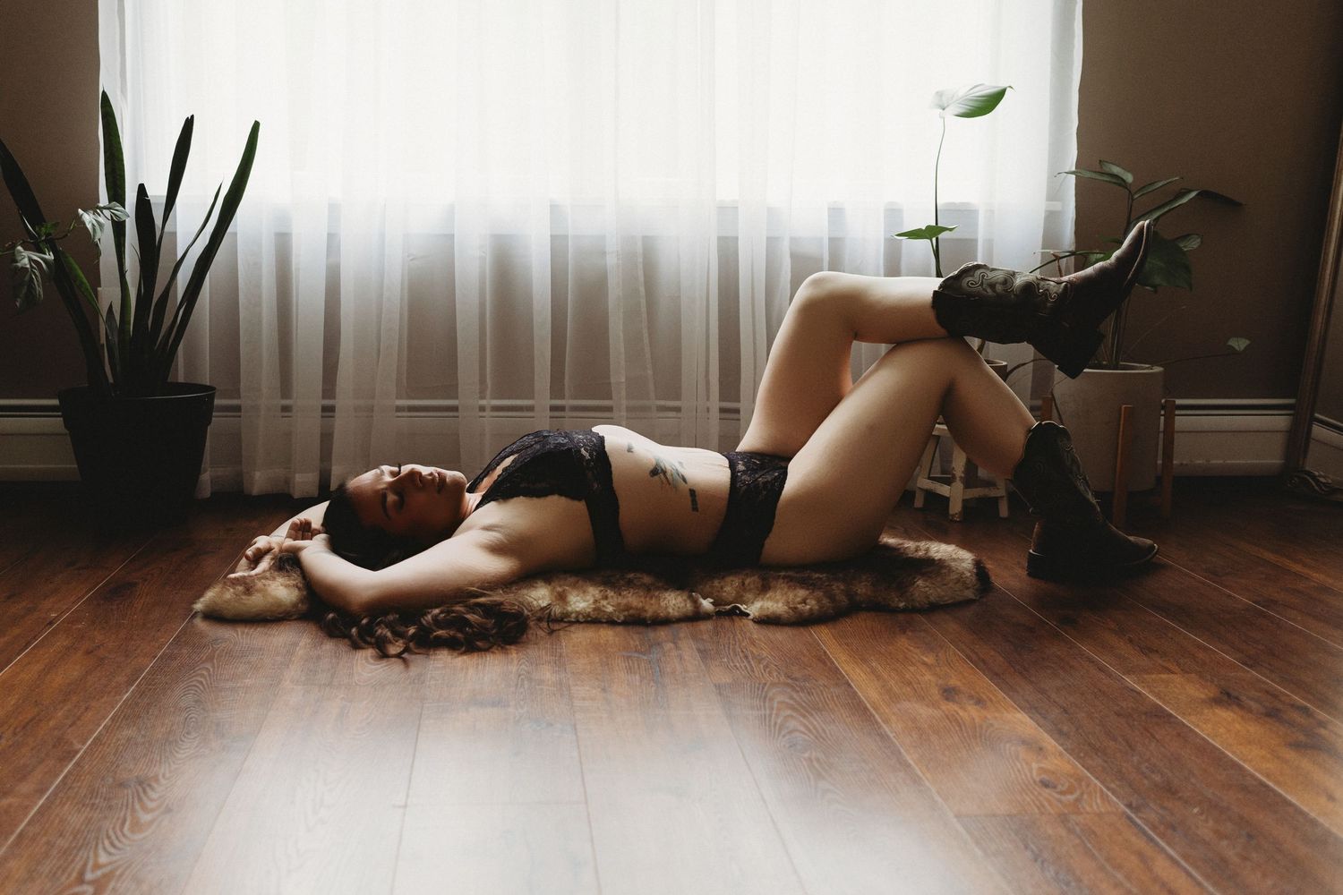 Professional boudoir photo of a woman laying on the ground with cowgirl boots