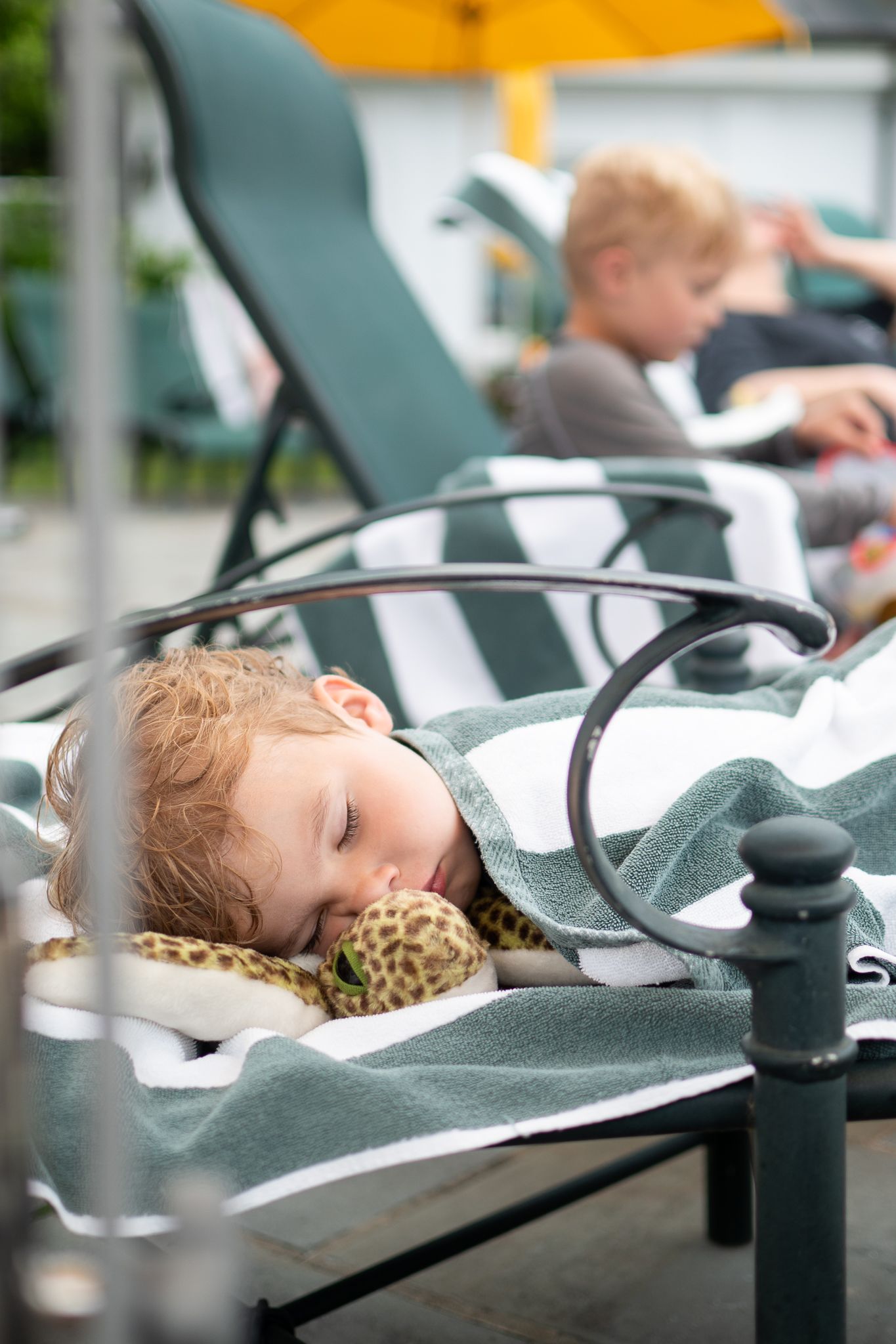 A child sleeps peacefully in a stroller while traveling outdoors on a sunny day.