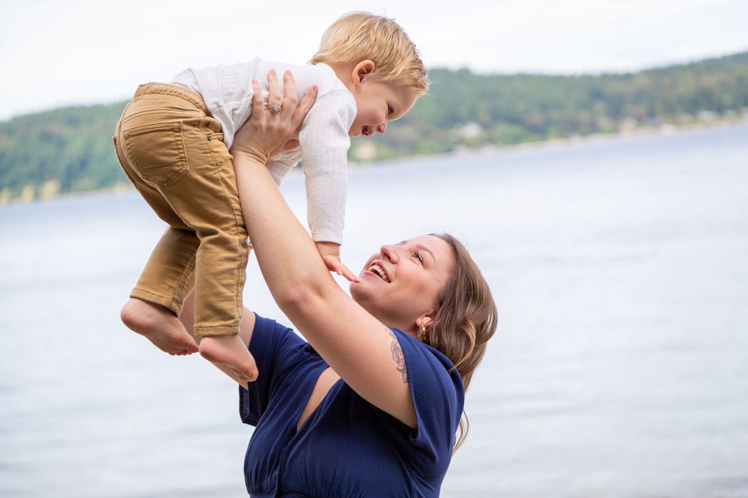 A joyful moment shared between parent and child playing together by a serene lake on a sunny day.