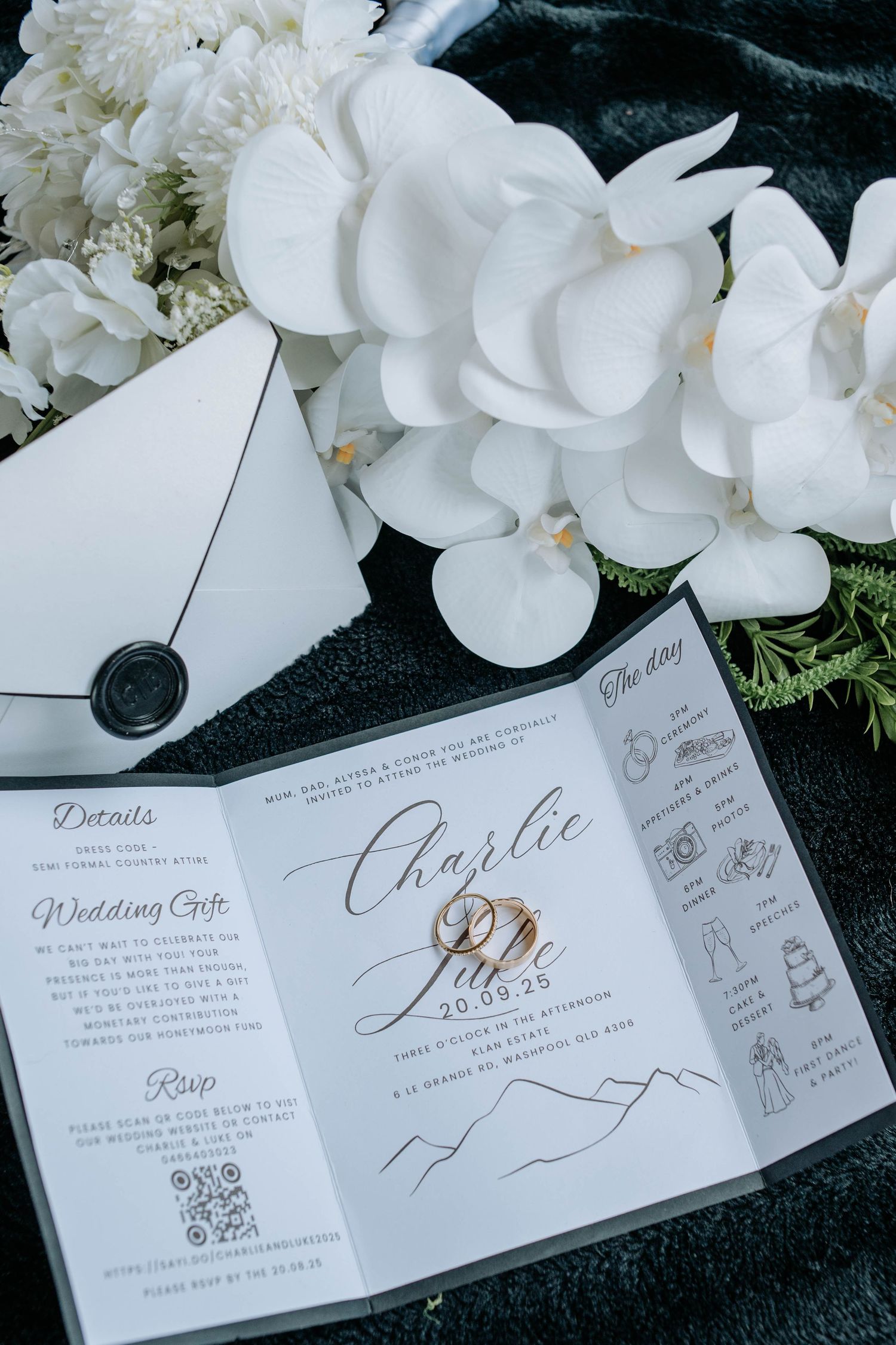 Elegant wedding invitations with white orchids and calligraphy displayed on a black background.