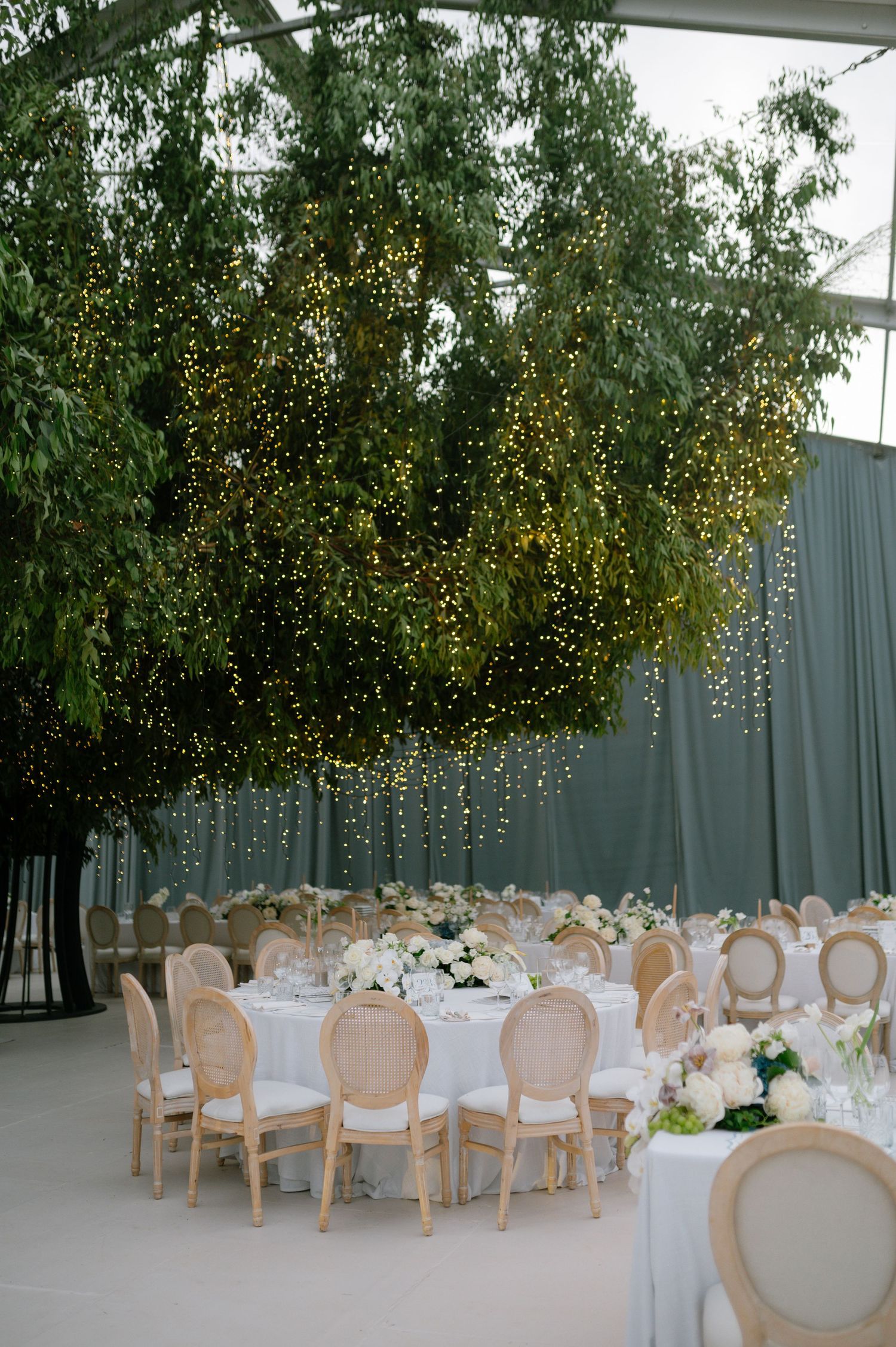 Elegant wedding reception venue with white chairs and hanging fairy lights creating a romantic atmosphere.