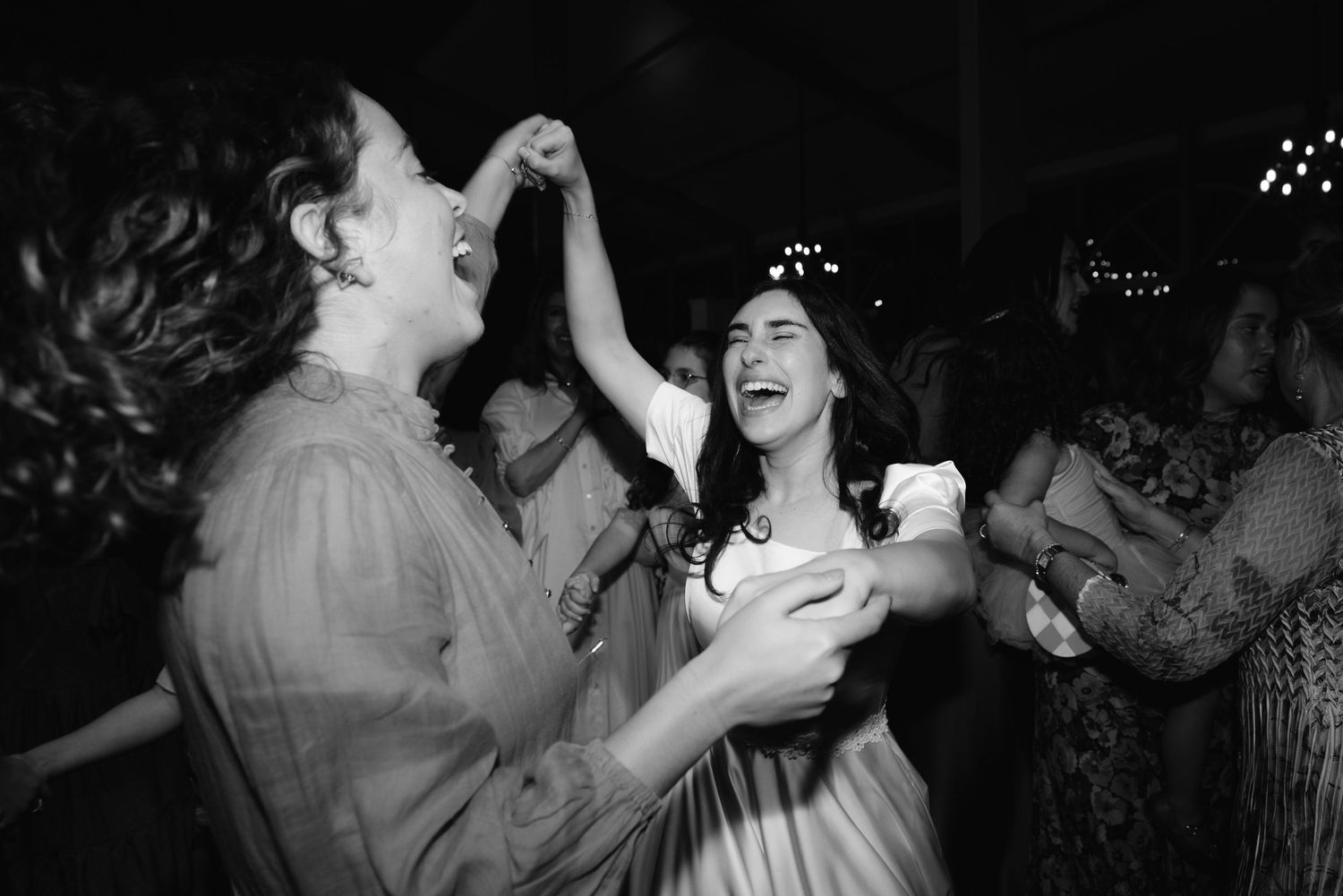 A black and white photo of two people dancing and laughing joyfully at a party or celebration.