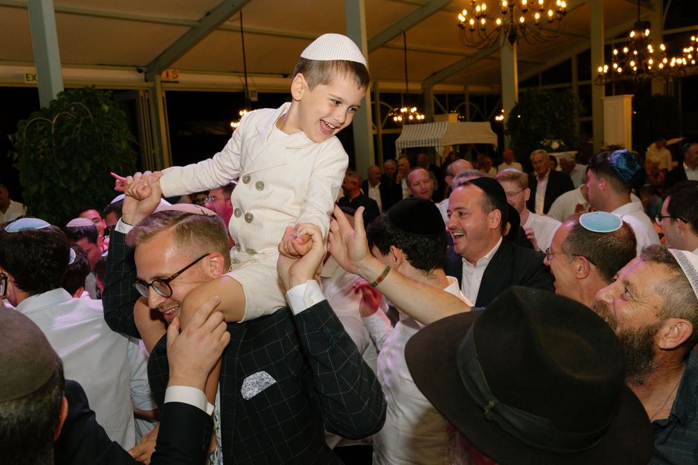 Wedding guests dancing and celebrating together on a crowded dance floor under warm lighting.
