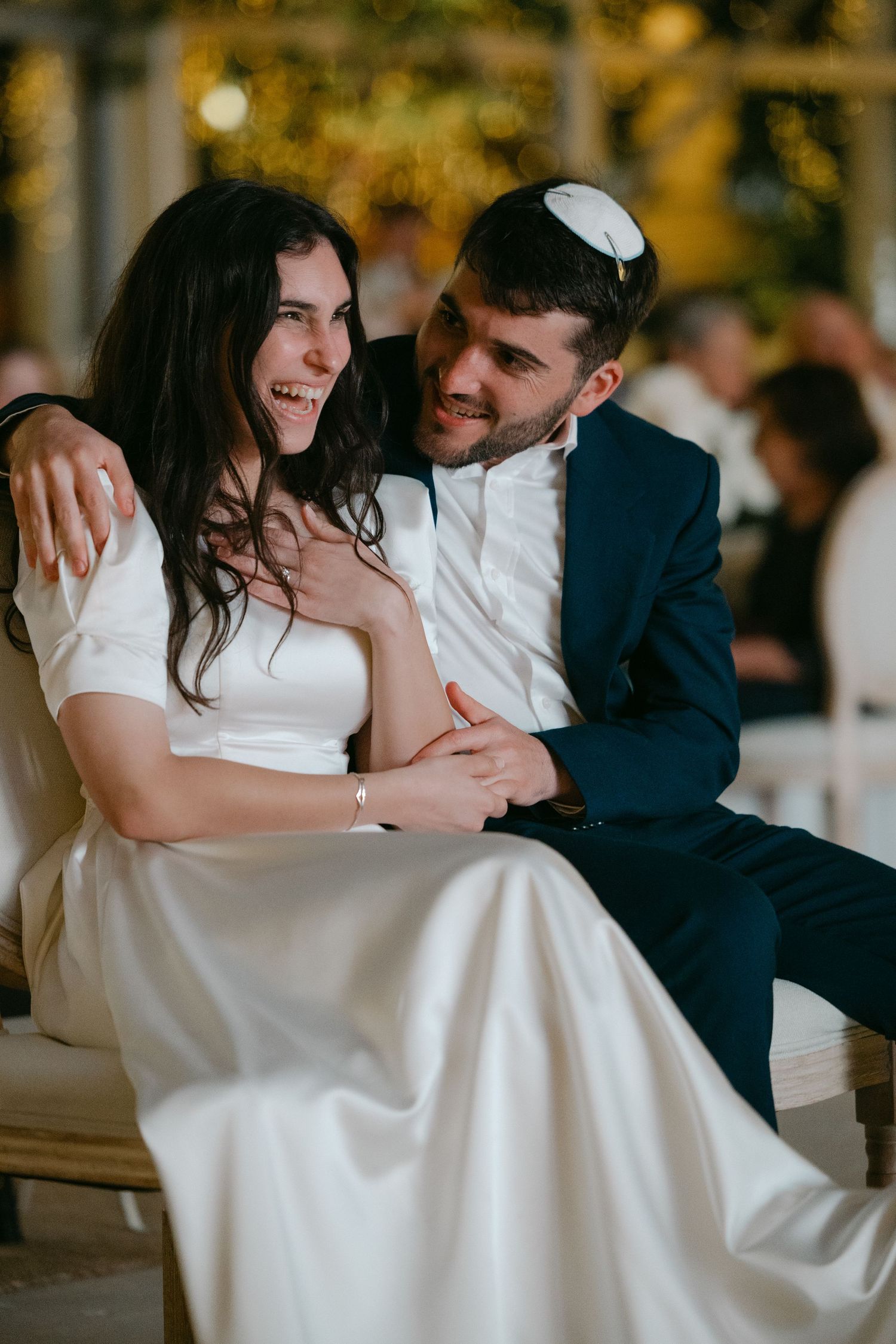 A couple sharing an intimate moment during their wedding reception while seated.