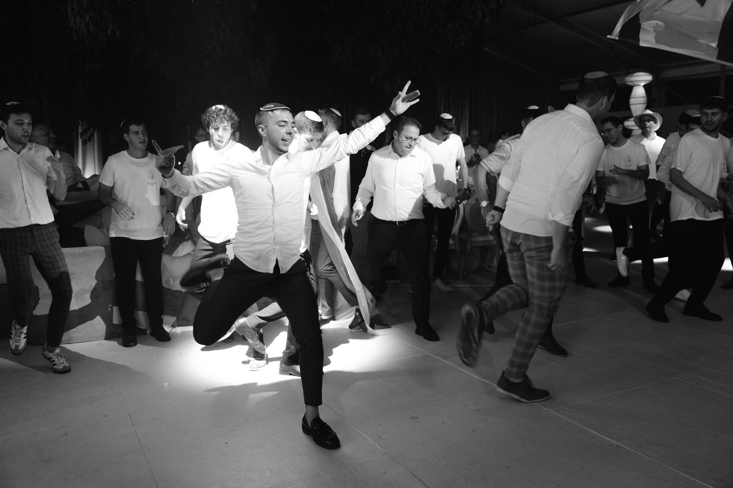 Black and white shot of people dancing and celebrating on a dimly lit dance floor.