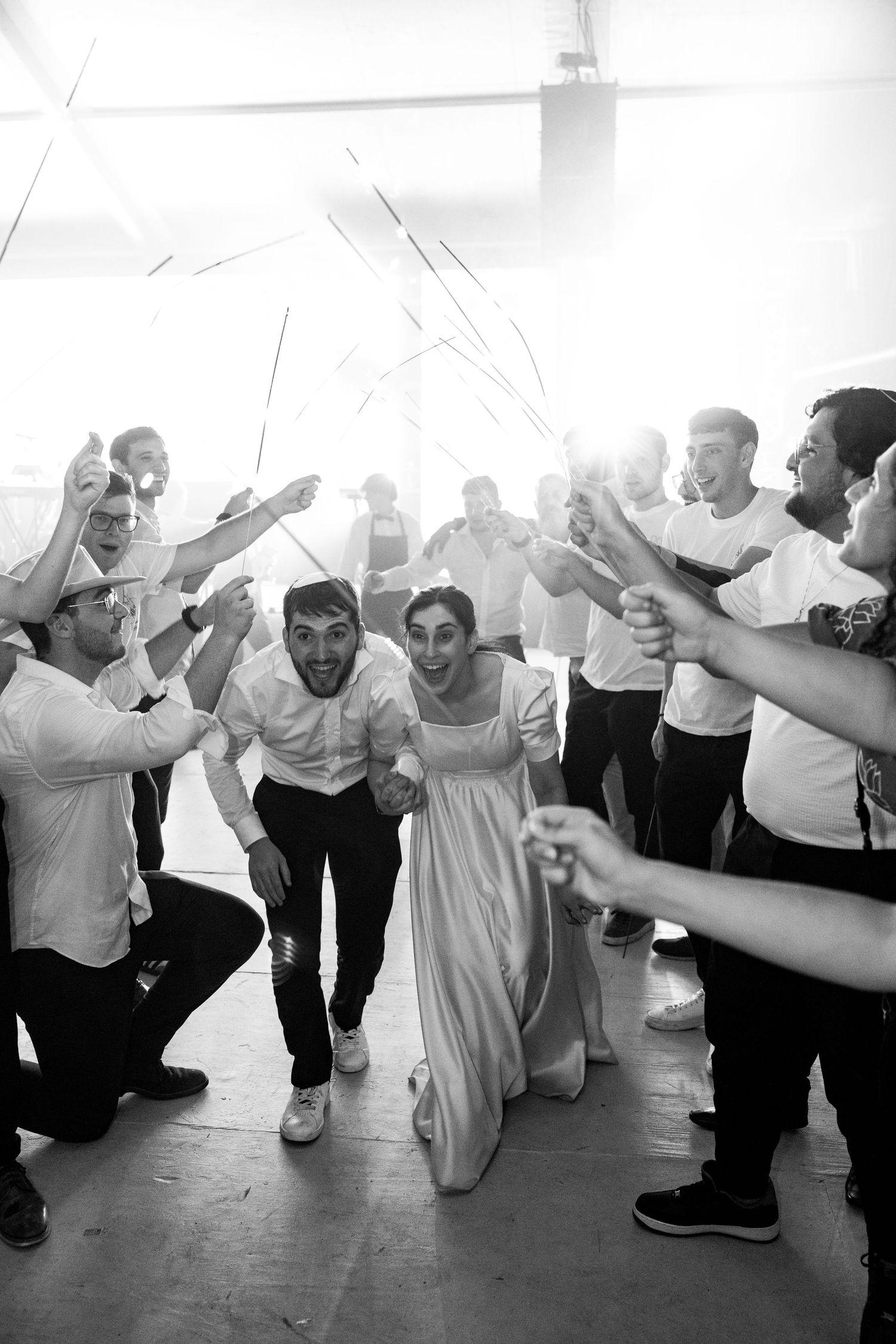 Wedding guests dancing in a line formation during a lively reception celebration in black and white.