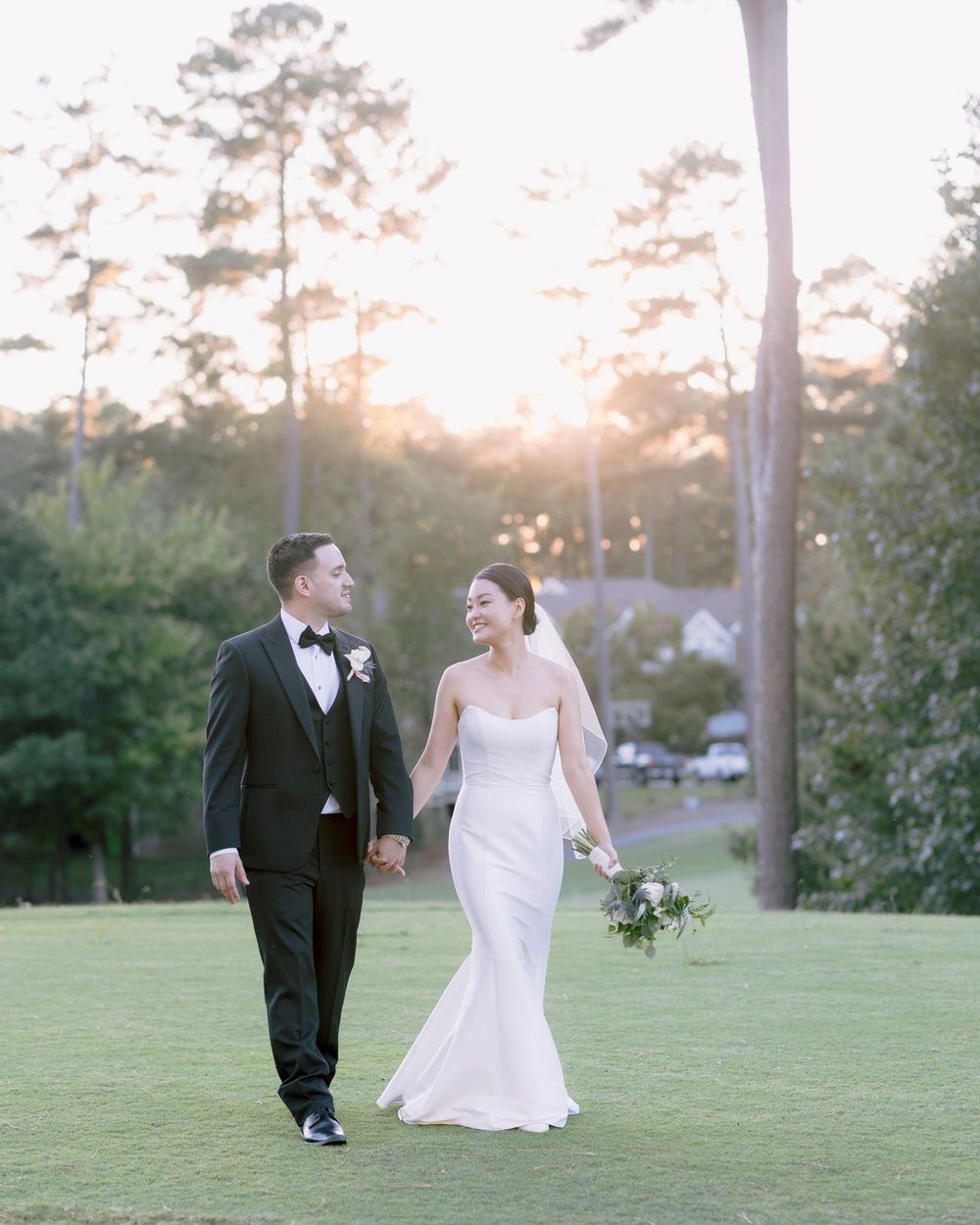Newlyweds walking together on a golf course during sunset.