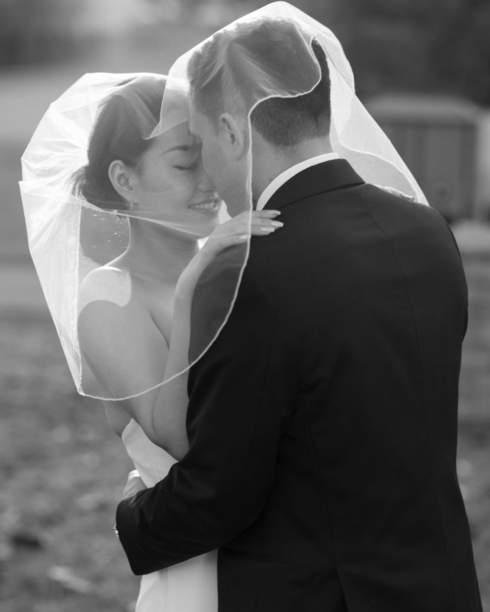 Intimate black and white portrait of wedding couple with flowing veil.