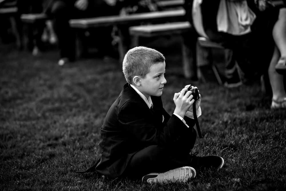 A series of black and white photos showing people sitting and interacting on grassy ground at an outdoor gathering.