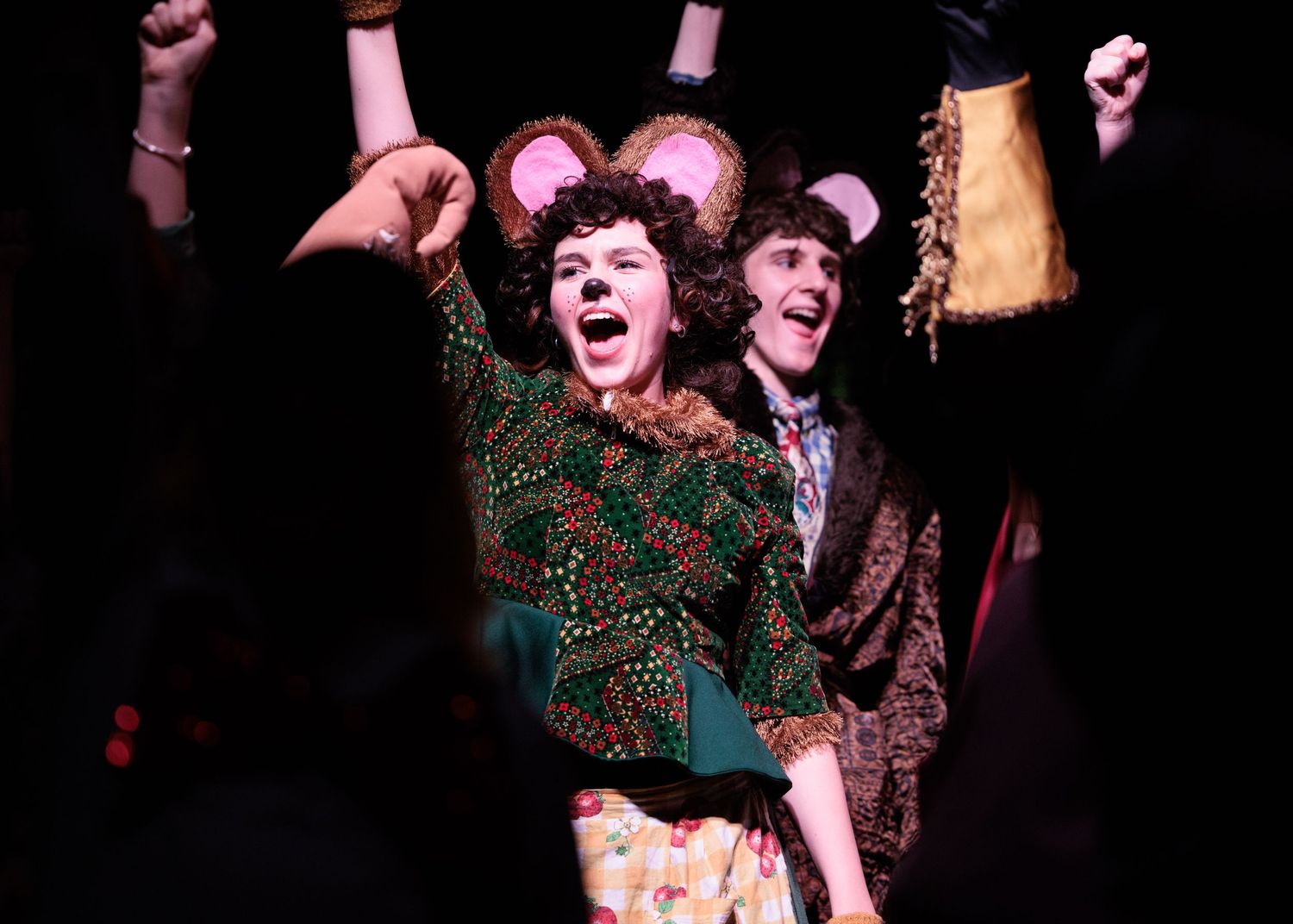 Theater actors perform dramatic scenes on a dark stage with expressive movements and gestures.