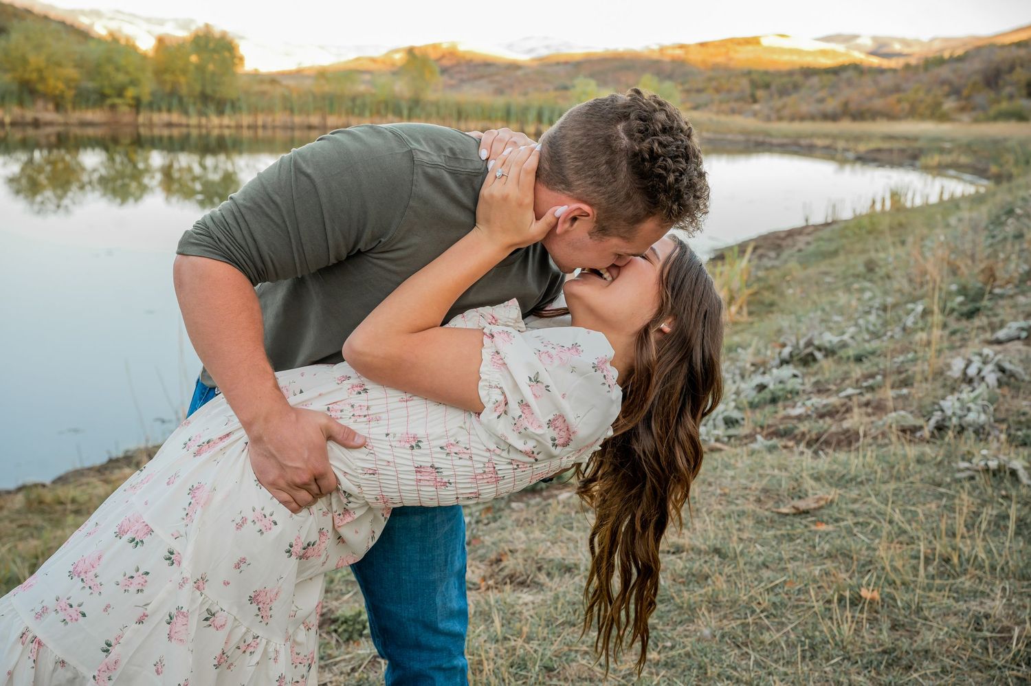 A romantic dip kiss by a serene lake during golden hour.