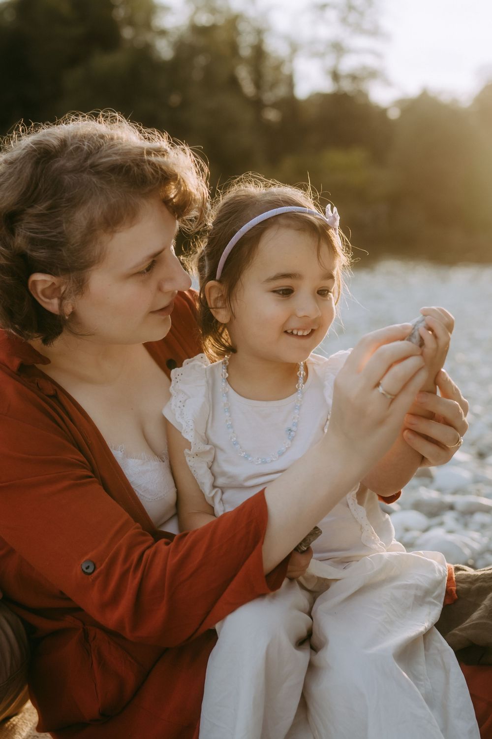 Tender moment shared while examining something together on rocky shoreline.