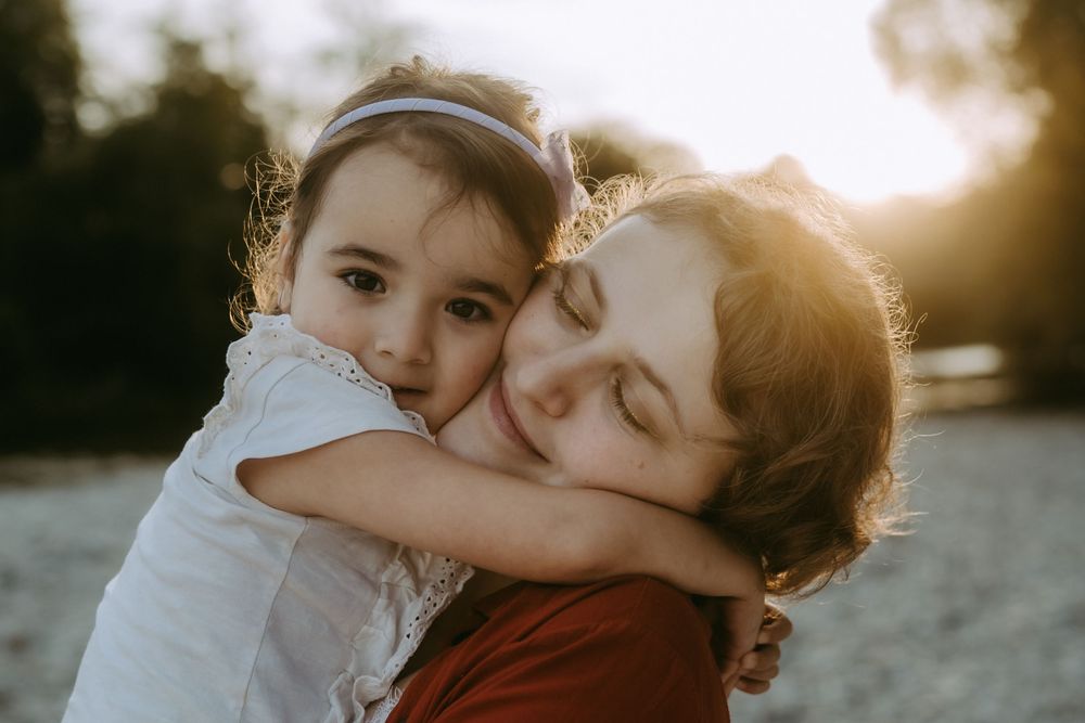 Tender outdoor photoshoot at sunset showing affectionate embraces on a rocky beach.