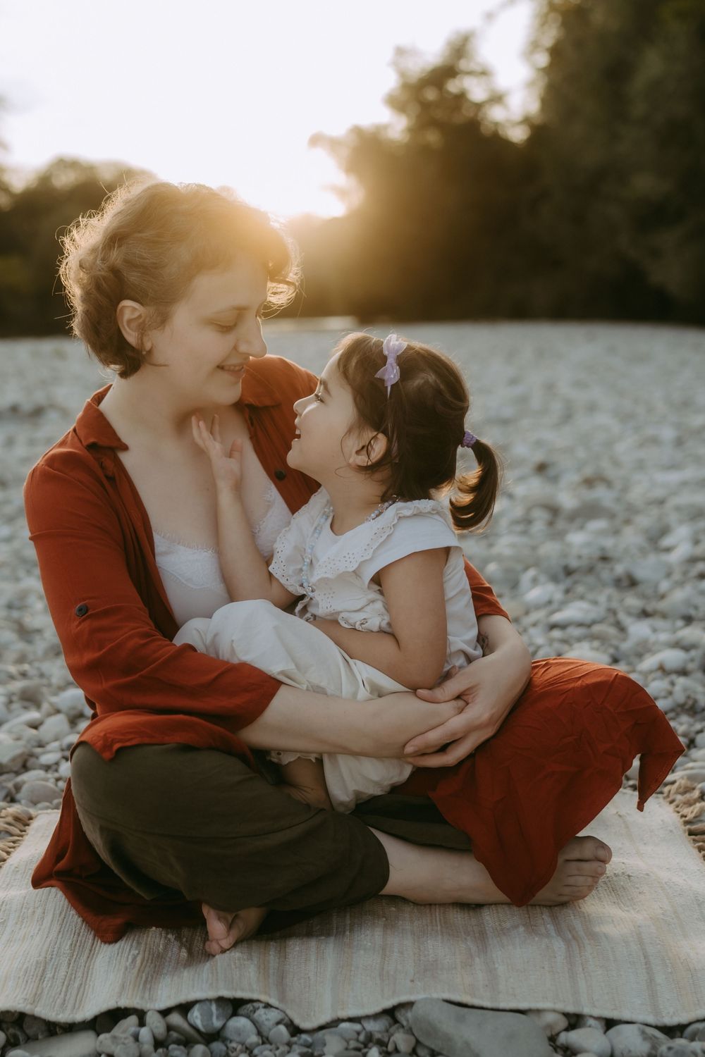 Intimate family moment captured during golden hour on a rocky shore.