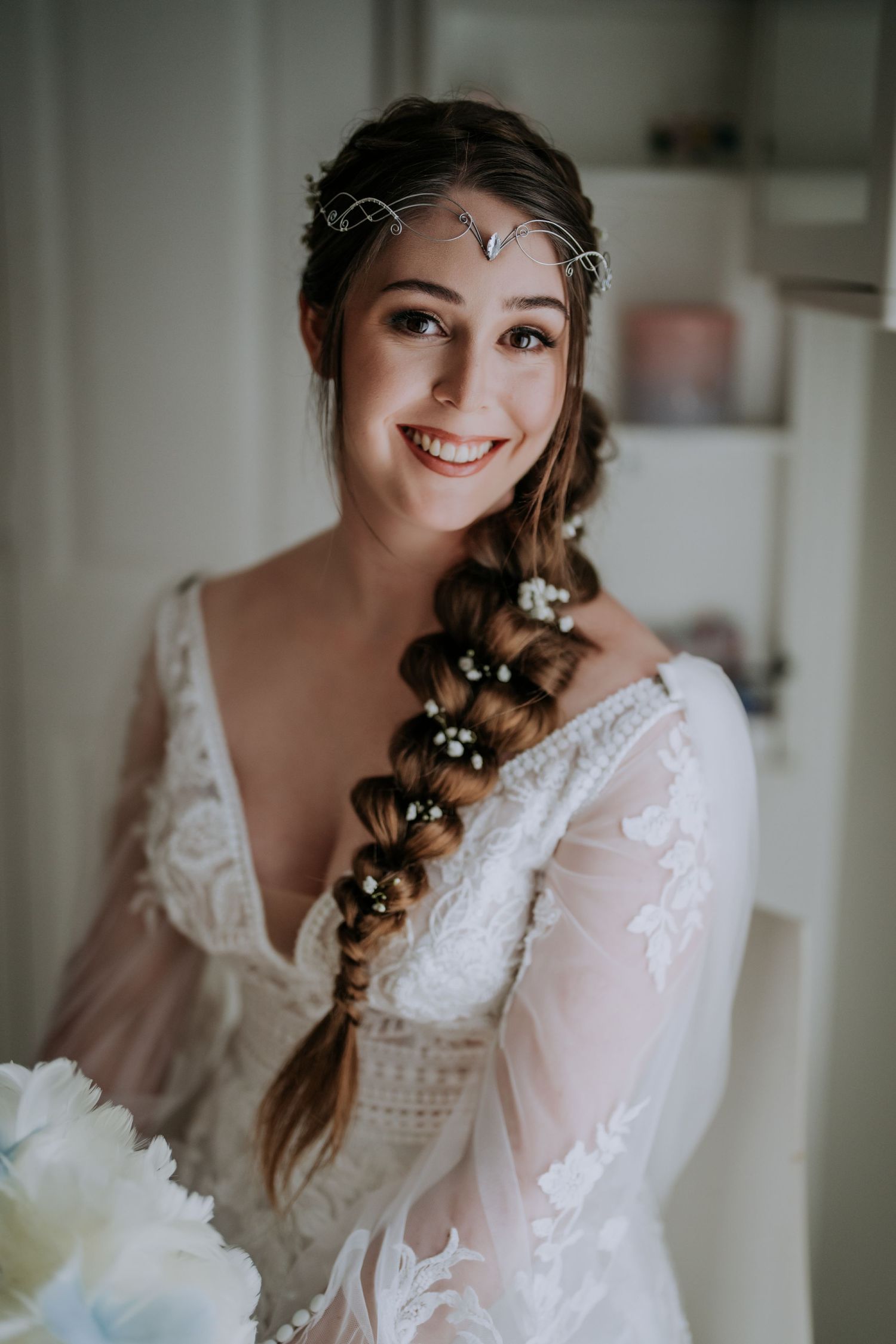 Bride wearing bohemian lace dress with braided hair adorned with delicate headpiece.
