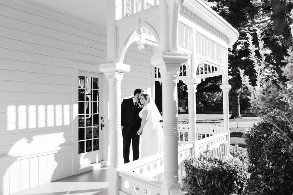 Elegant white veranda with ornate trim and columns creates a romantic wedding venue backdrop.