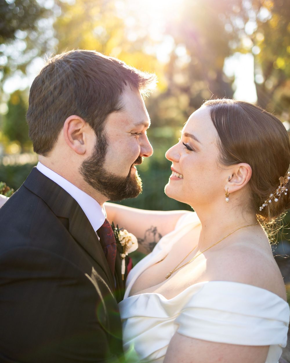 A romantic wedding couple shares intimate moments in golden sunlight during an outdoor photoshoot.