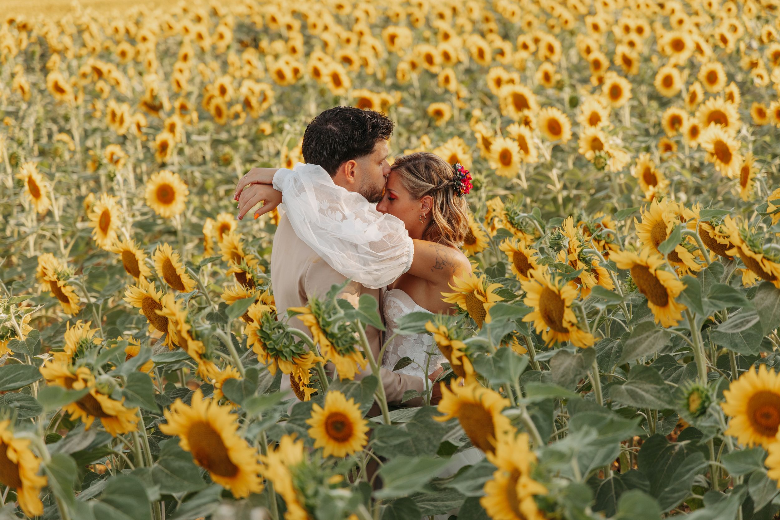 Couple embracing romantically in a vibrant sunflower field.