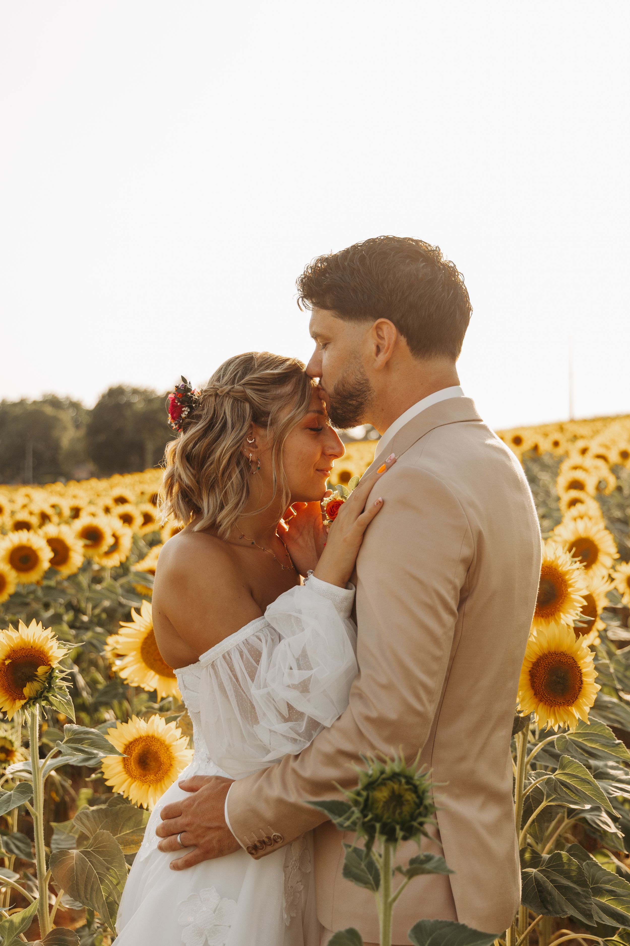 Elegant bride and groom sharing an intimate moment in a sunflower field.