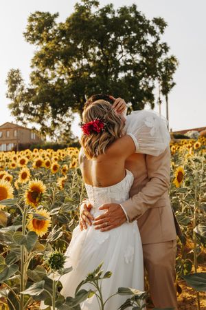 Bride and groom embracing with backs to camera in a sunflower field.