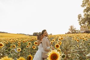 Bride and groom standing together gazing across a vast sunflower field during golden hour sunset.