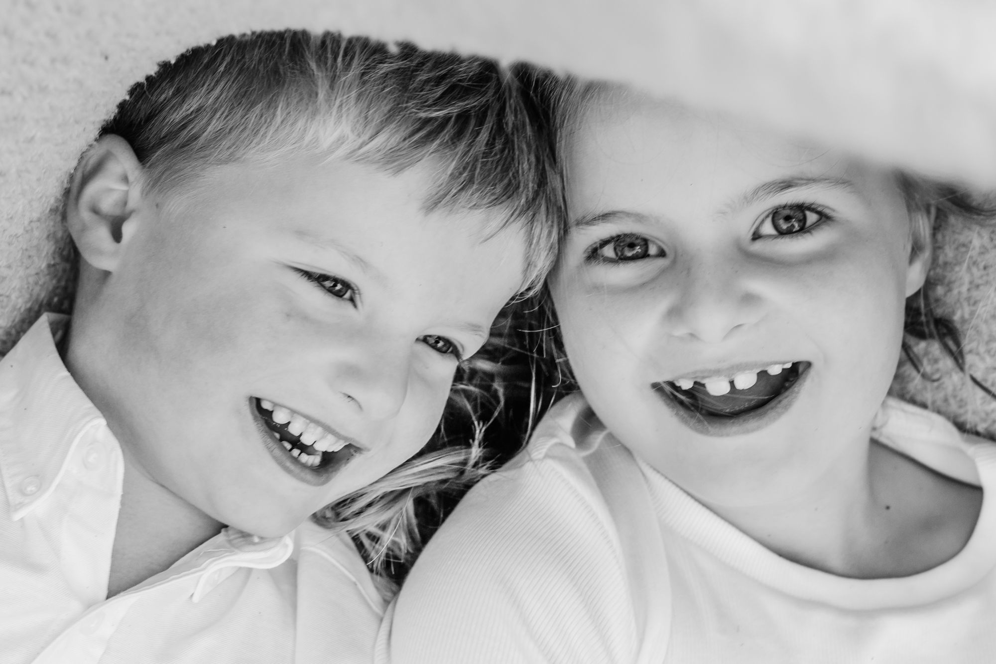 A black and white collage of children's smiling faces arranged in a horizontal row.