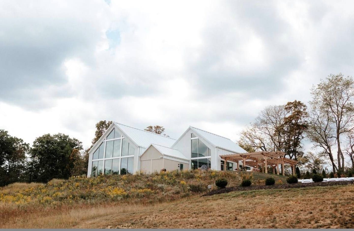 Panoramic view of greenhouse-style wedding venue buildings on a hillside.