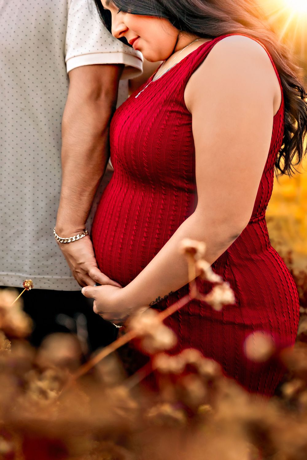Fresno, CA maternity photographer captures a tender moment between parents to be in a detail shot with the sun bright behind them.