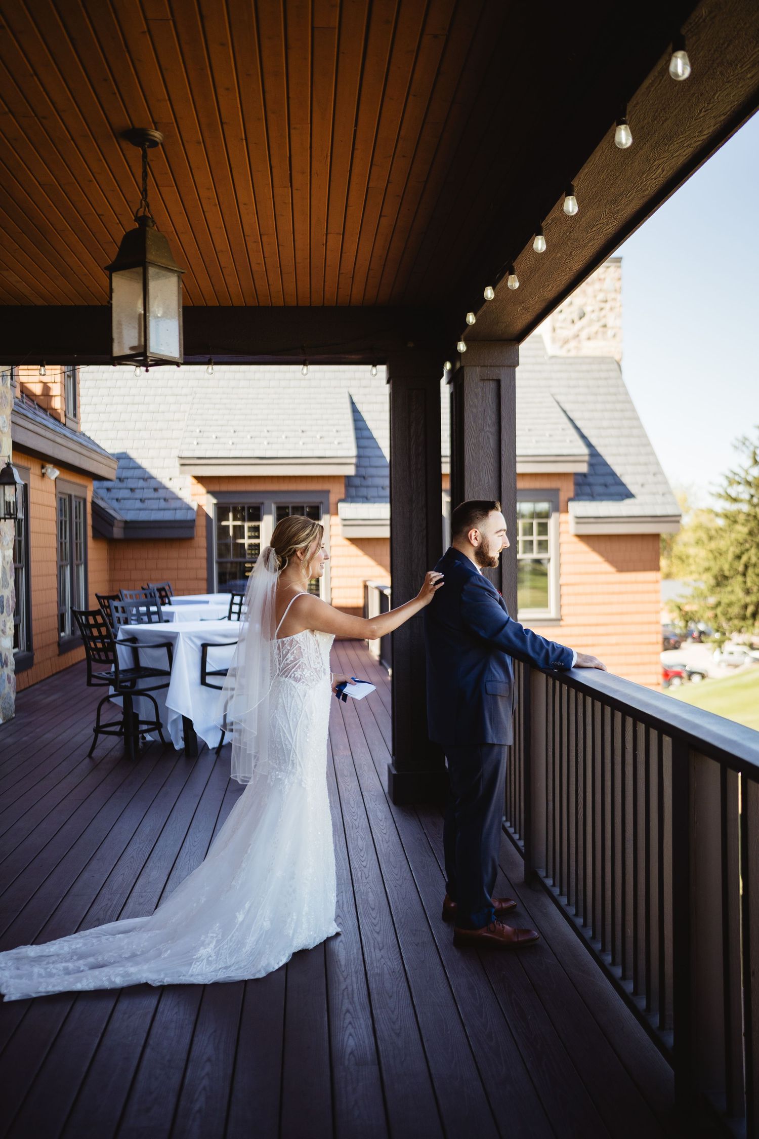 A couple shares a romantic first look moment on a covered wooden porch during their wedding day.